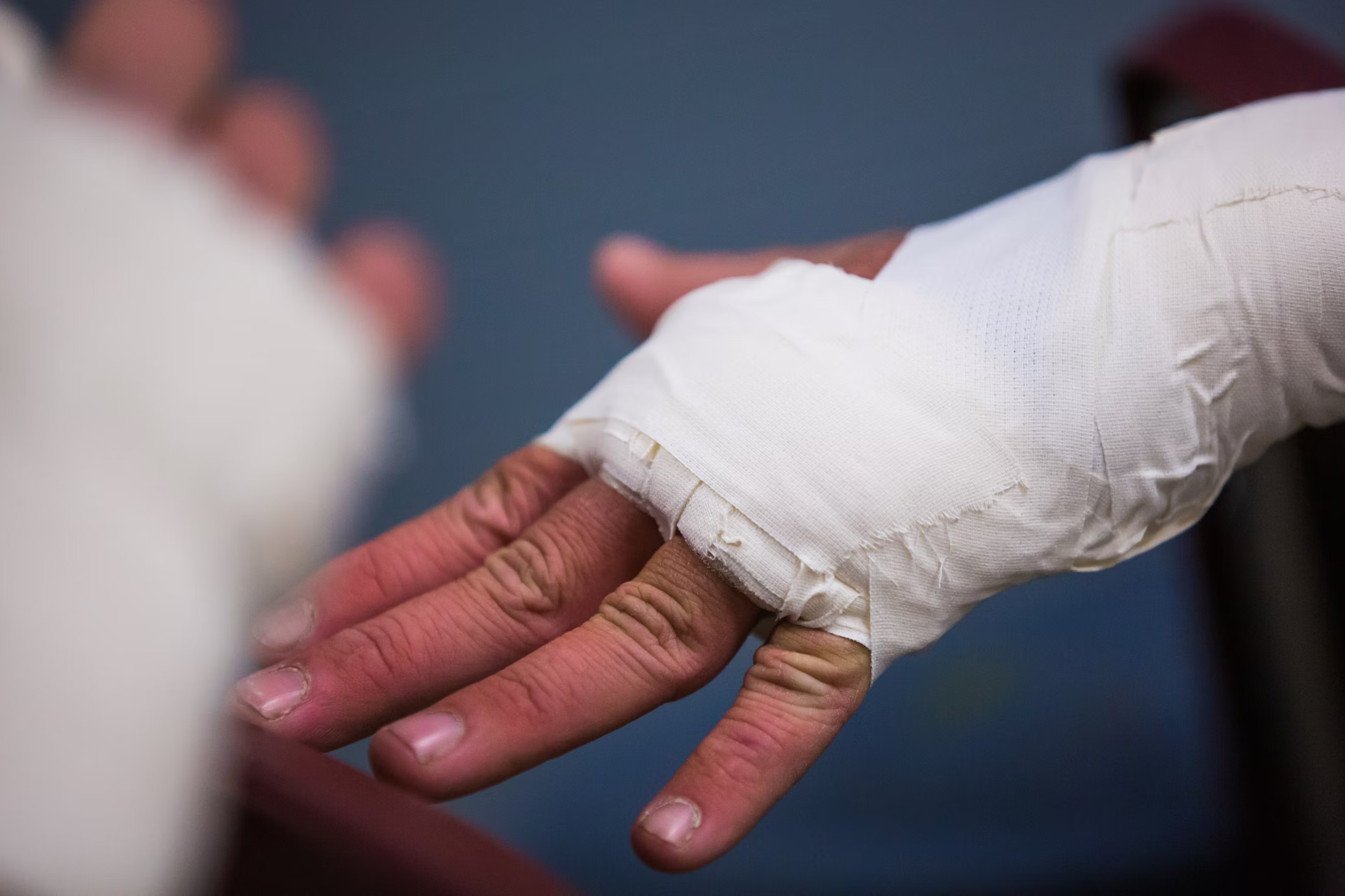 A bandaged hand resting in the open palm of another person