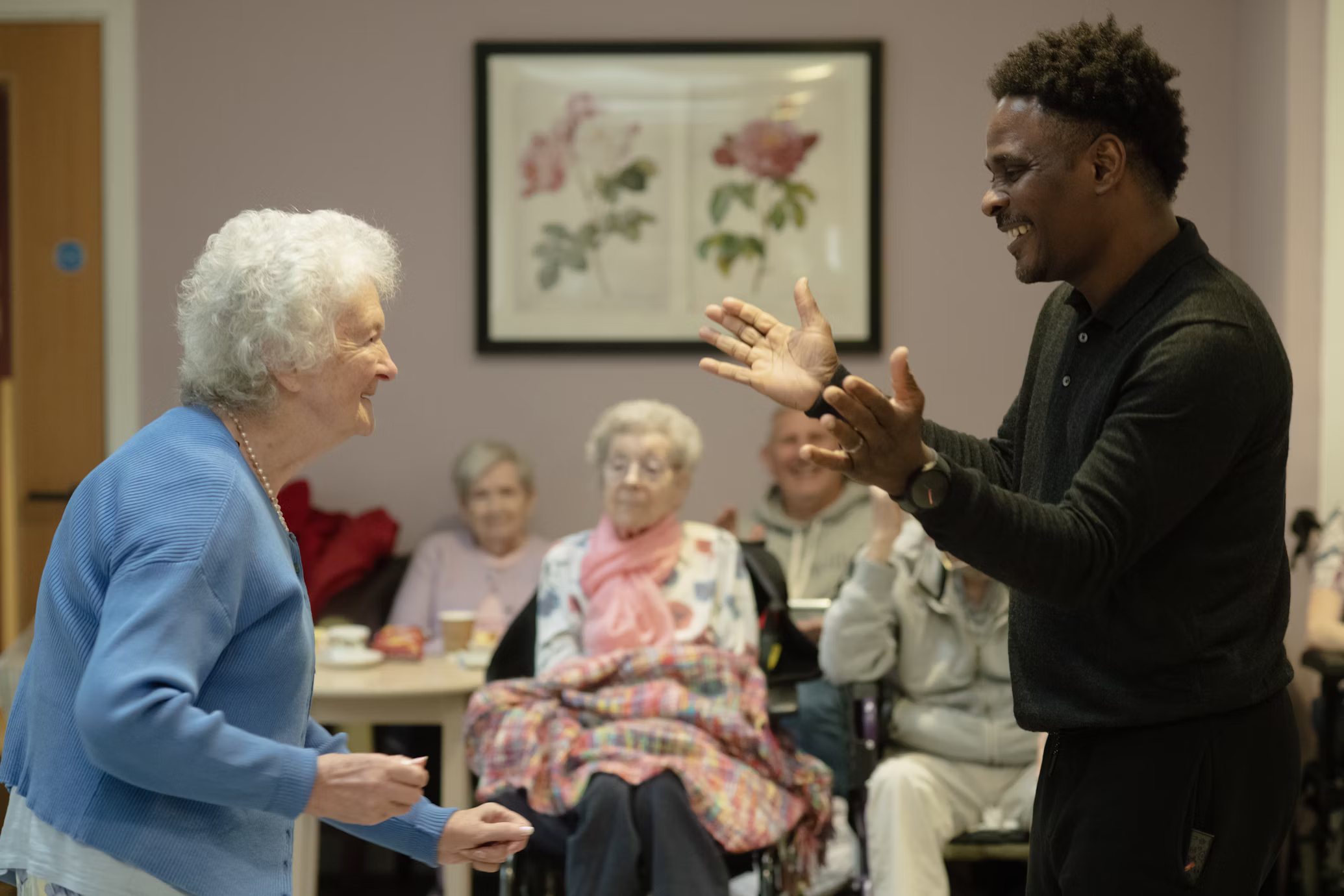 Caregiver and resident sharing a moment in a senior care facility common room