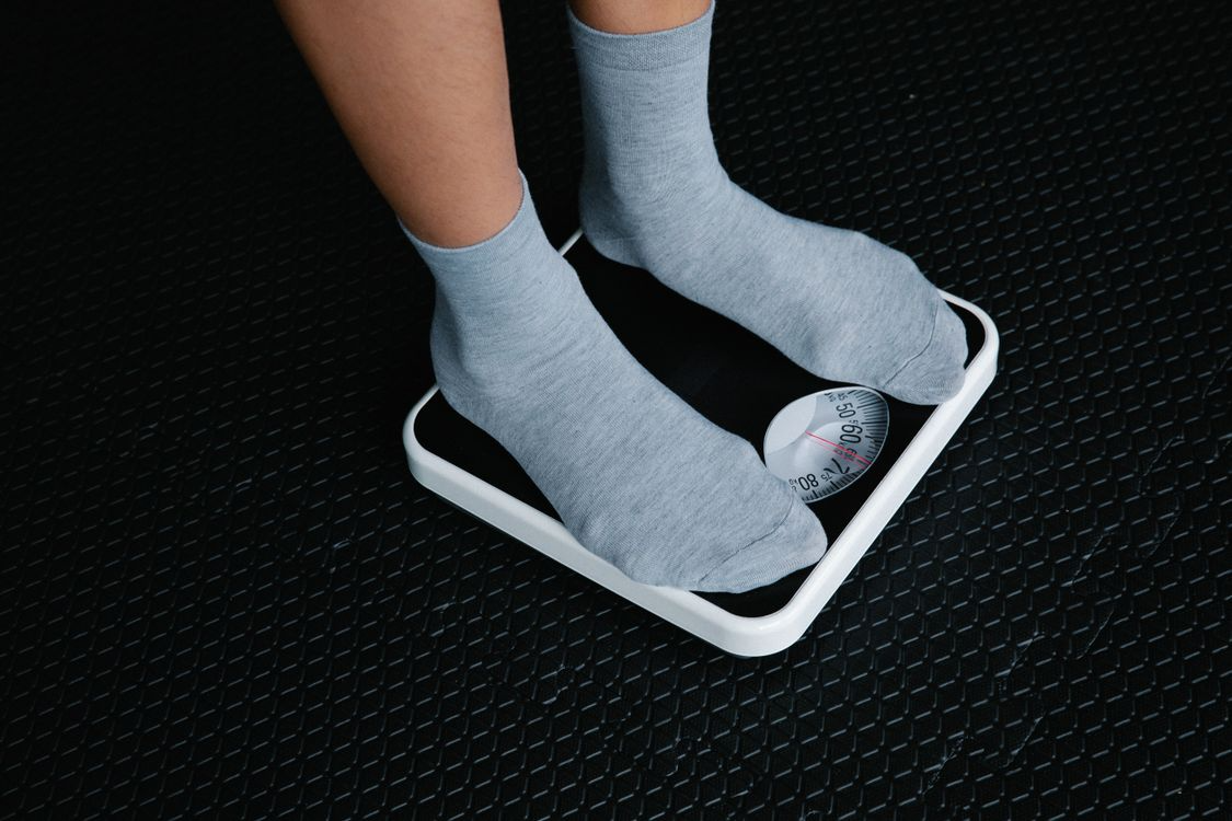 A person in gray socks standing on a bathroom scale