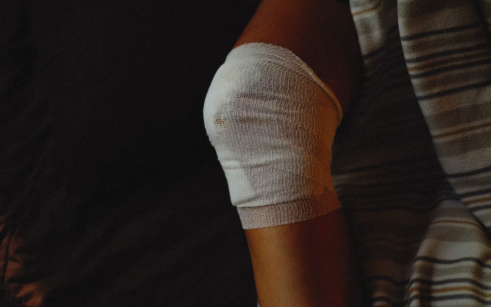 A clean white bandage wrapped around an upper arm in warm light