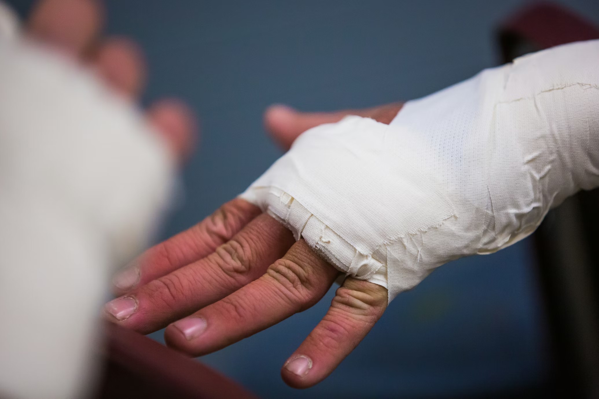 A bandaged hand held gently in the open palm of a caregiver